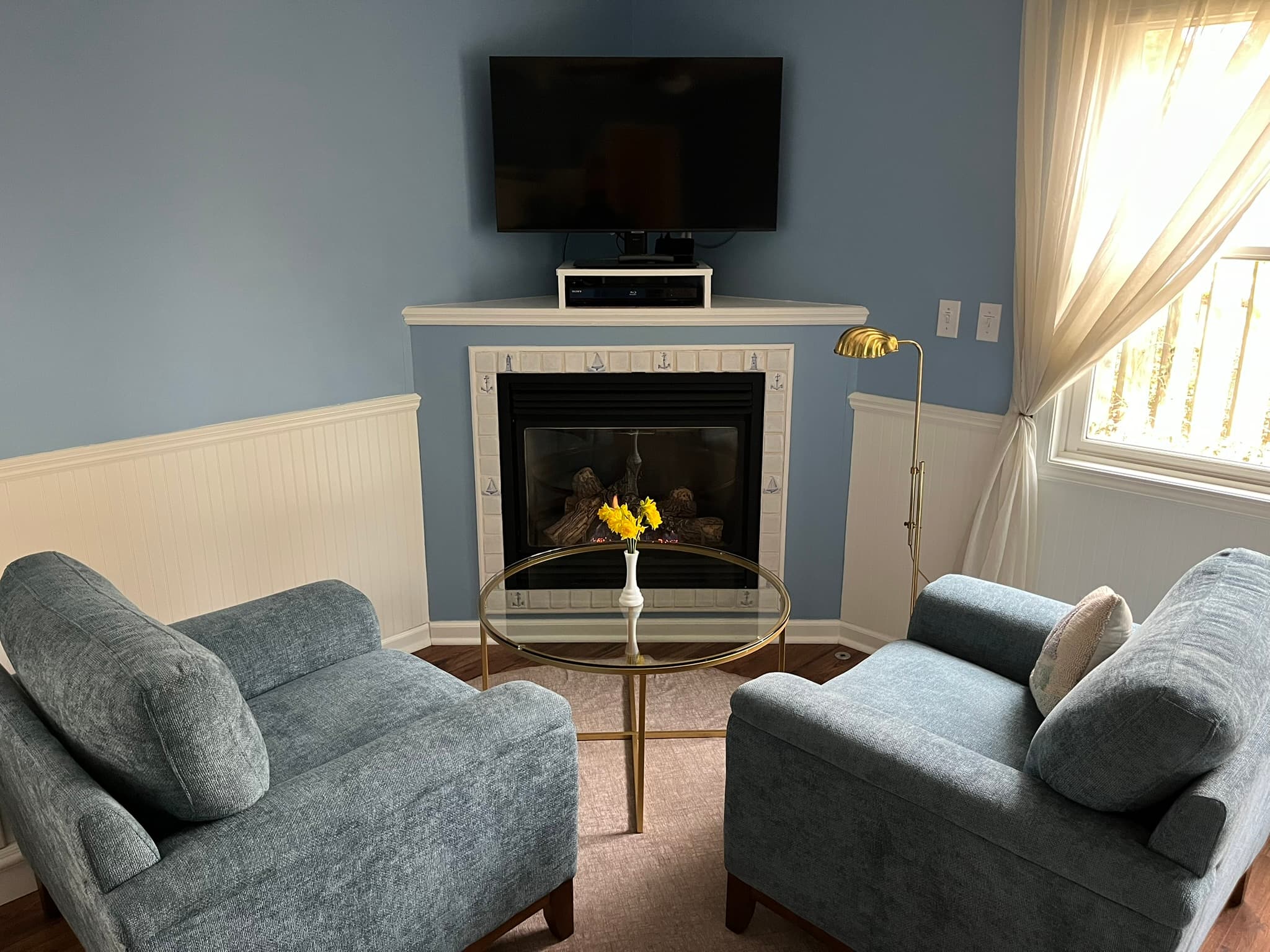 2 Chairs and table in front of fireplace and TV