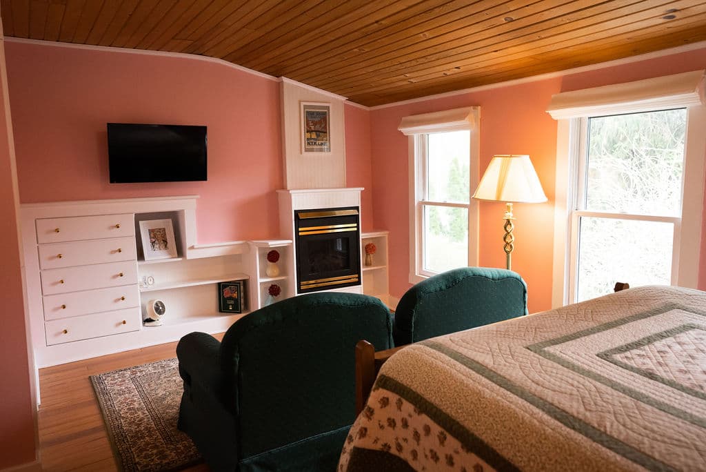 Rose room sitting area with window, fireplace and flat screen TV