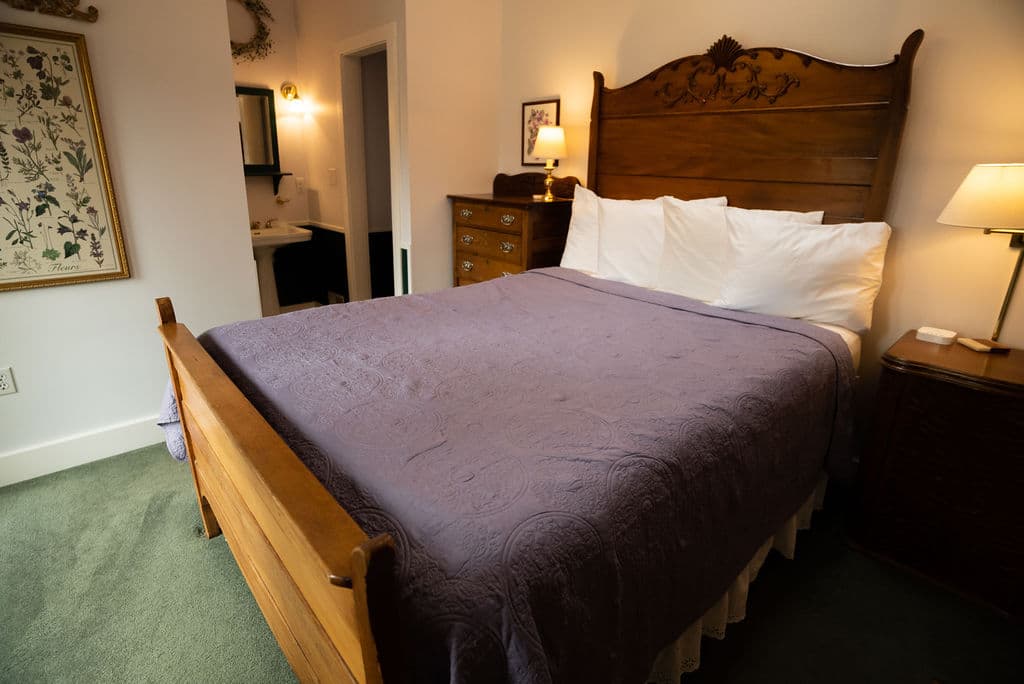 Queen size bed with tall oak headboard and four deluxe pillows