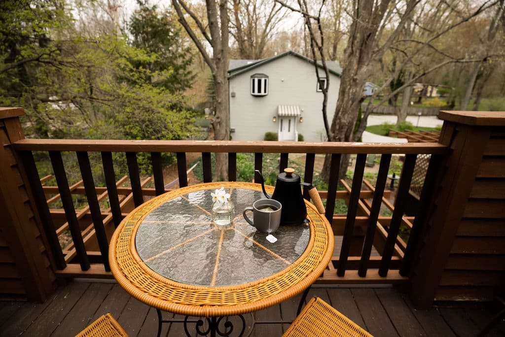 Private balcony with seating for two and center table overlooking the shade garden