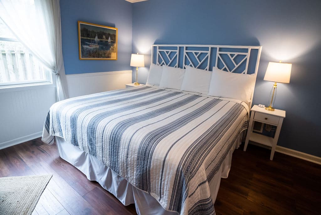 View of king bed against blue wall with nightstands & lamps on both sides