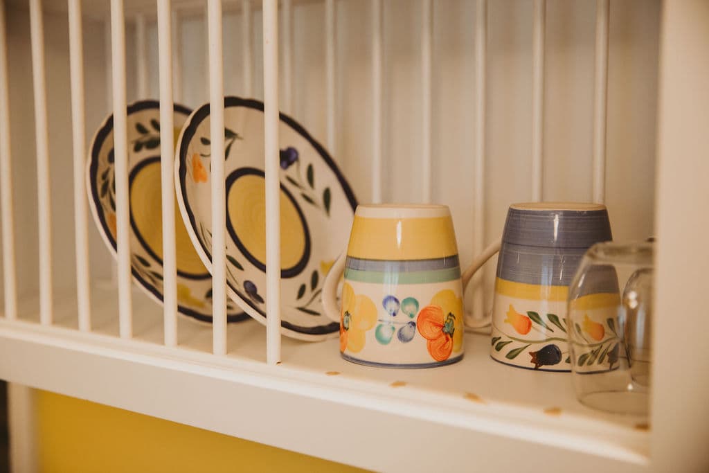 Kitchenette Dish shelf with two colorful plates, two wine glasses and two coffee mugs