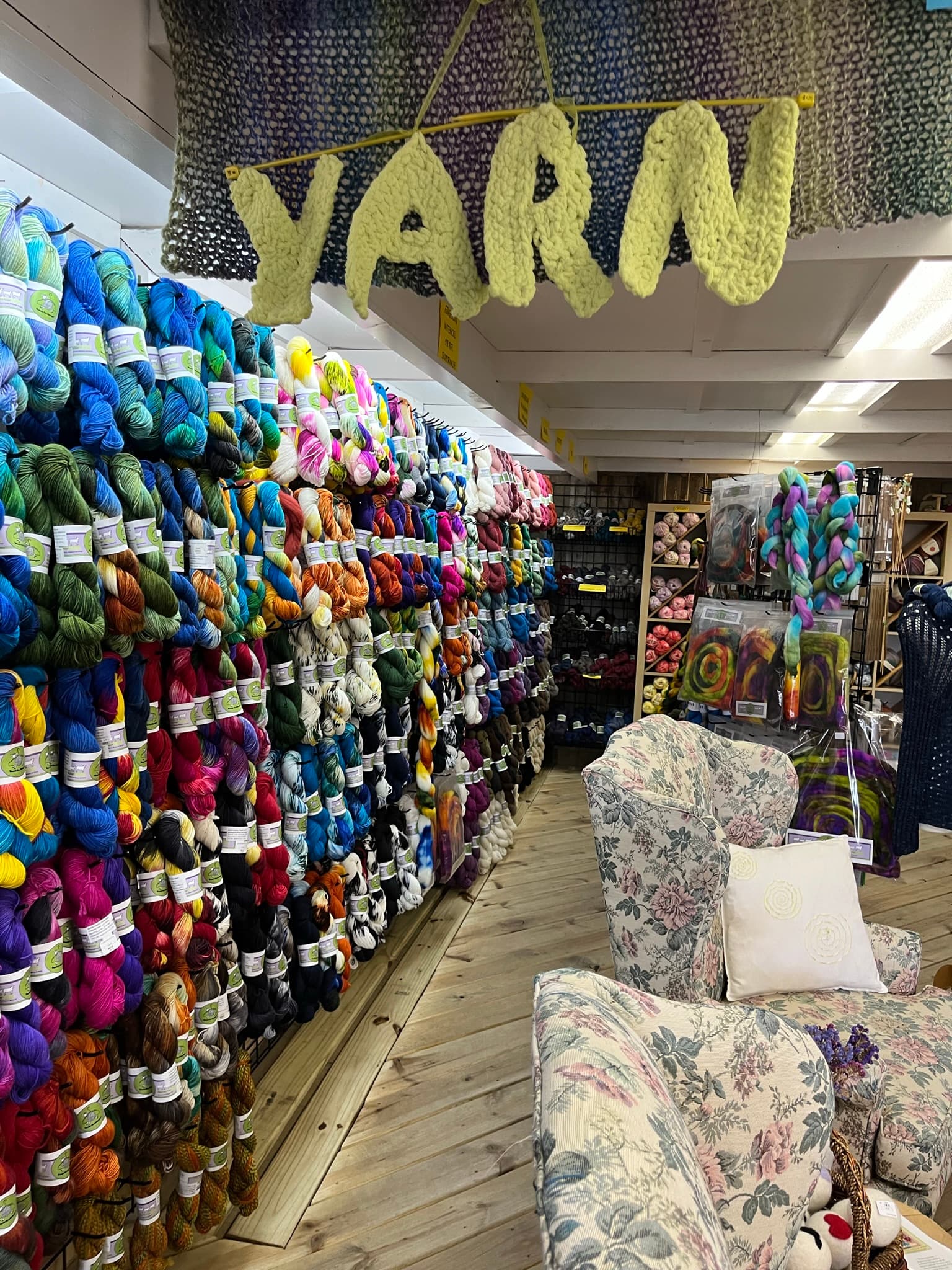 A colorful array of yarnskeins displayed on shelves in a cozy craft store.