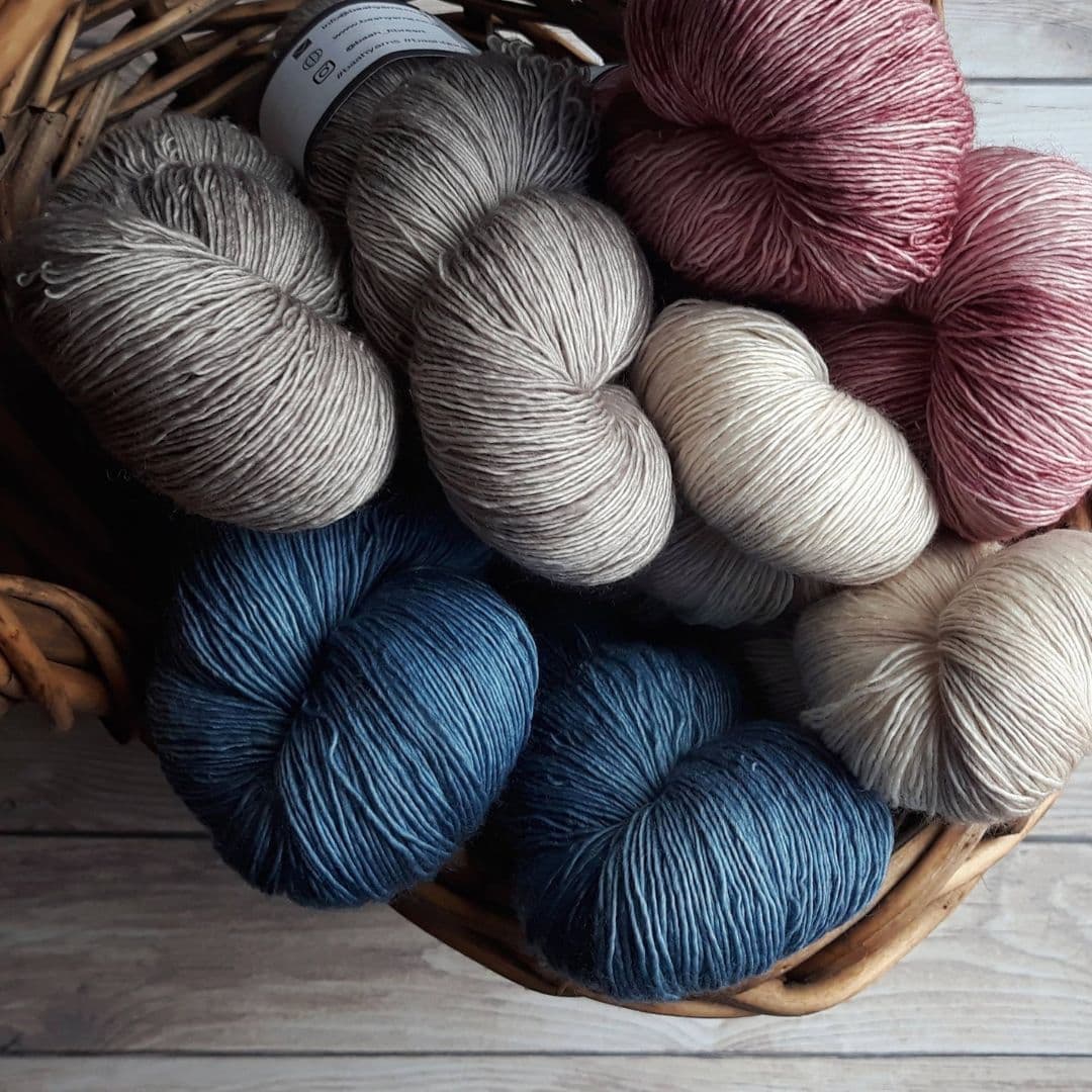 Basket of yarn in red, greys and blues.