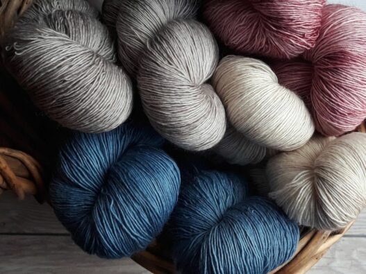 Basket of yarn in red, greys and blues.