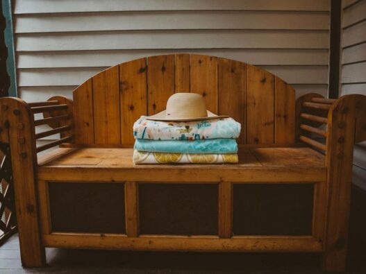 Beach hat set on three towels on an outdoor bench